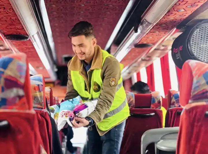KBM volunteer handing out snacks to pilgrims on a bus