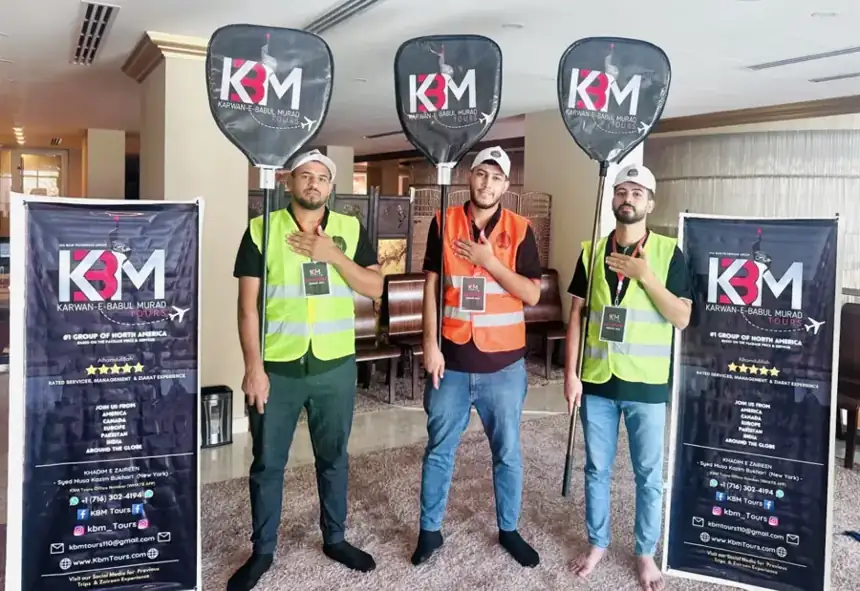 Three KBM volunteers with hands on their hearts between KBM Tours banners