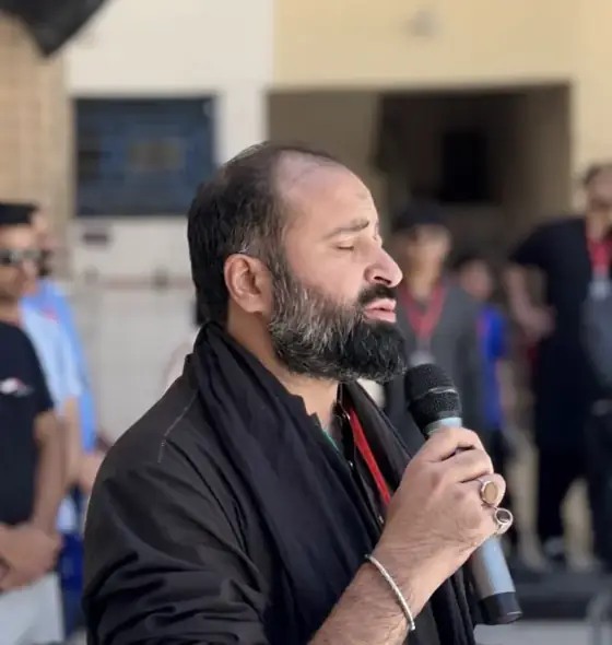 Mir Kazmi reciting into a microphone during a KBM Tours ziyarat