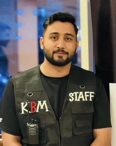 Br. Toqeer in a KBM Staff vest beside a KBM Tours banner