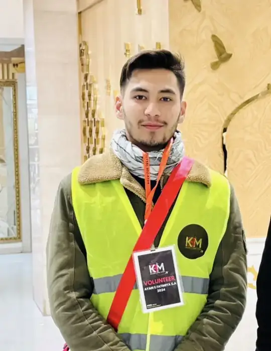 KBM volunteer in a yellow vest with a KBM volunteer badge