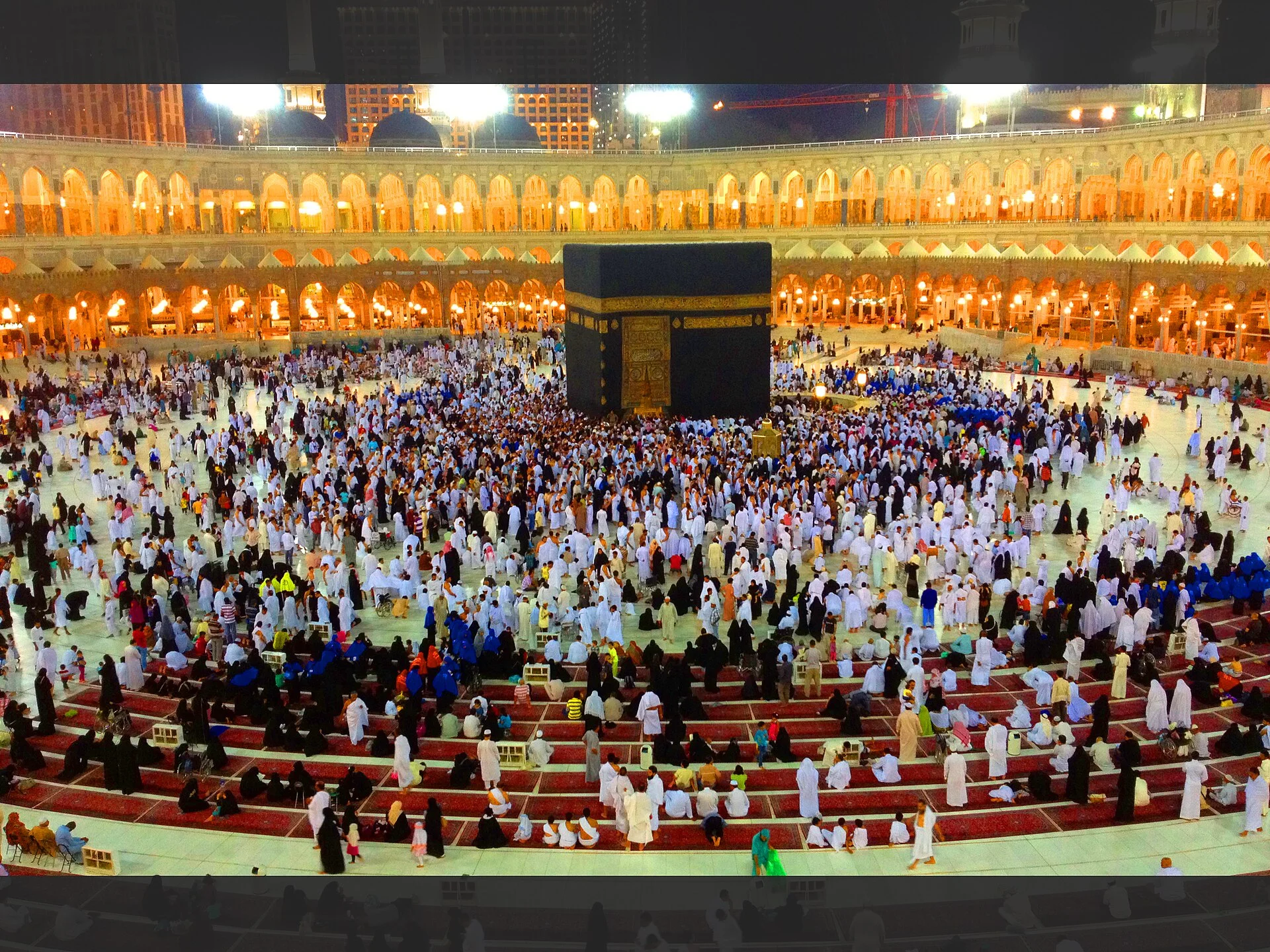 The Kaaba in Masjid al-Haram at night, surrounded by pilgrims